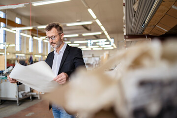 Businessman with plan in factory warehouse
