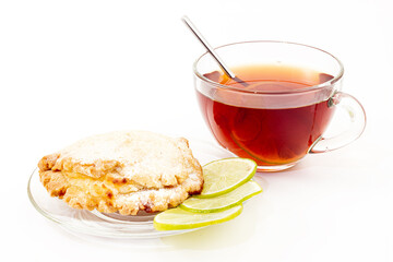 Still life of sochen with cottage cheese and lime on plate and cup of black tea on white background. Pastries from shortcrust pastry in the form of a flatbread folded in half with a half-open filling