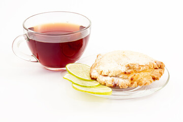Still life of sochen with curd and slice of lime on plate and cup of black tea on white background. Pastries from shortcrust pastry in the form of a flatbread folded in half with a half-open filling