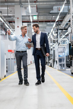Two businessmen with tablet talking in a modern factory