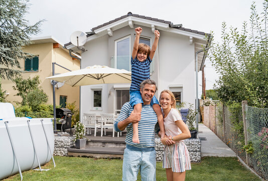 Portrait of father with wife carrying son on shoulders in garden