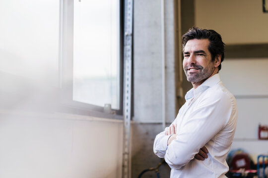 Portrait of a smiling businessman at the window in a factory