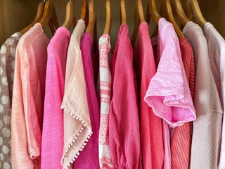 Assorted pink tops, blouses, shirts and t-shirts hanging in a wardrobe