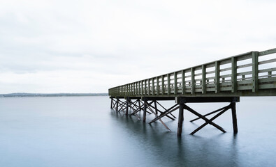 Obraz premium Wooden dock or Pier over the tranquil misty seawater in New Haven Harbor in Connecticut