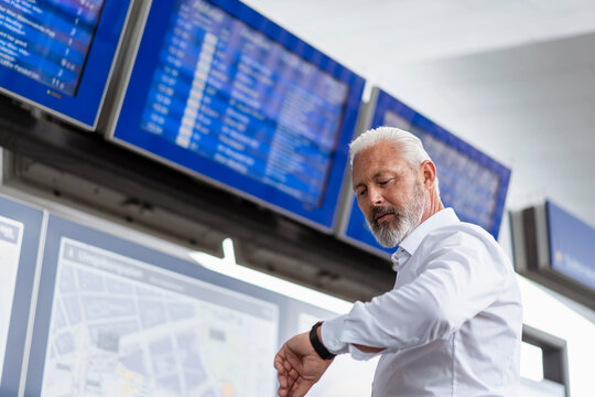 Mature businessman checking the time at departures board