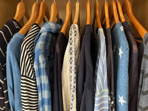 Assorted blue tops, blouses, shirts and t-shirts hanging in a wardrobe