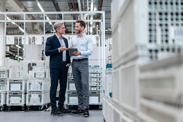 Two businessmen with tablet talking in a modern factory