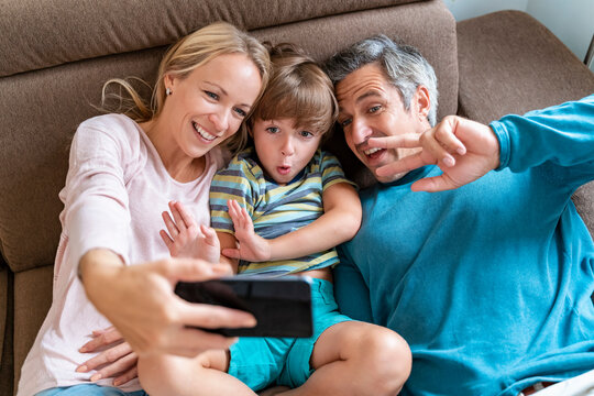 Father, mother and son taking a selfie on couch at home