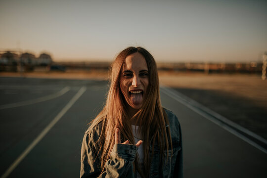 Portrait of young woman outdoors sticking out tongue