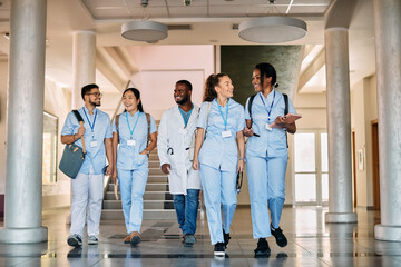 Happy multiracial medical students talk while walking through corridor of medical university.