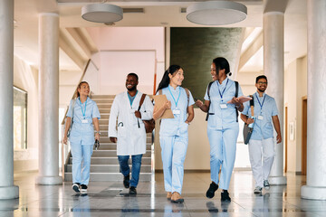 Multi-ethnic group of happy medical and nursing students walk through hallway and talk.