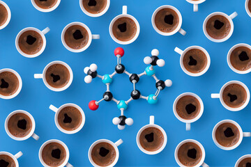 Directly above view of caffeine chemical formula with coffee cups over blue background