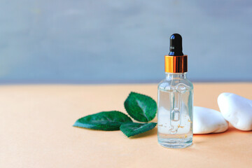 Cosmetology product for facial care. Serum in glass bottle with pipette on stone. Essential oil for care of female skin. Skin care, moisturizing beauty product on color background. 