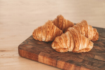 Croissants fresh baked pastries from french bakery. 4 viennoiseries on wooden board. Breakfast food from France baking culture. Flaky warm croissant.