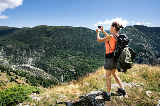 Switzerland, Valais, woman taking picture during a hiking trip in the mountains from Belalp to Riederalp