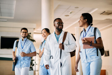Group of happy medical students talk while walking through hallway at the university.
