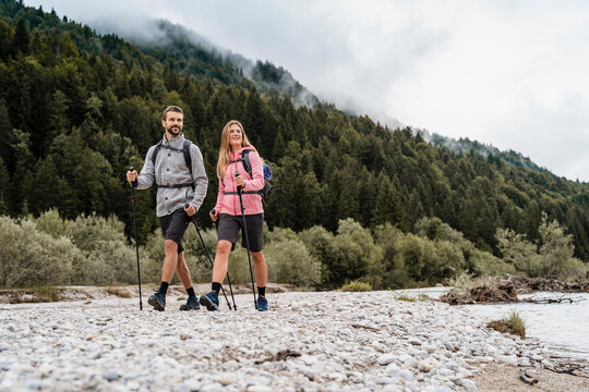 Young couple on a hiking trip at riverside, Vorderriss, Bavaria, Germany - Powered by Adobe