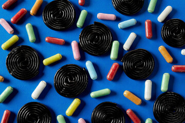 Spiral wheels of licorice candy with sugar coated licorice on blue background
