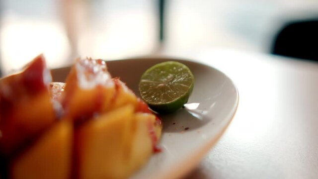 Plate of chopped mango with Mexican chamoy sauce and blurry background