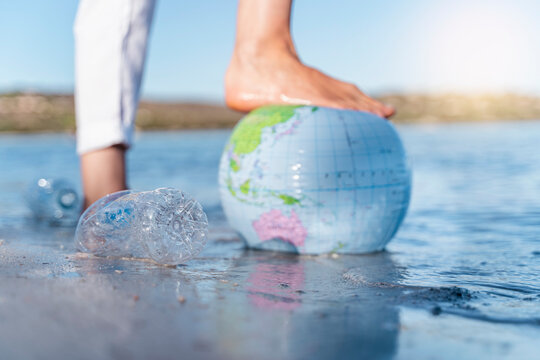Man's foot on Earth beach ball, close-up