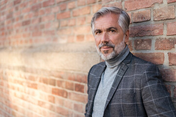 Portrait of fashionable mature businessman at a brick wall