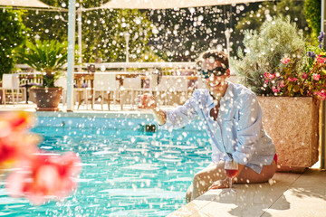 Mature woman sitting at poolside splashing with water