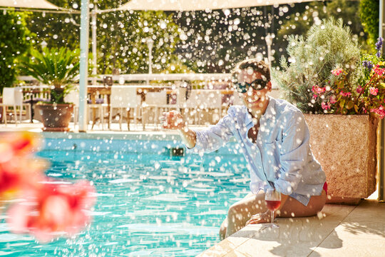 Mature woman sitting at poolside splashing with water