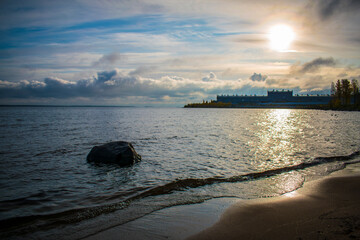 Sandy beach with boulders on the background of the rising sun