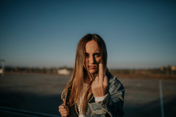 Portrait of young woman outdoors giving the finger