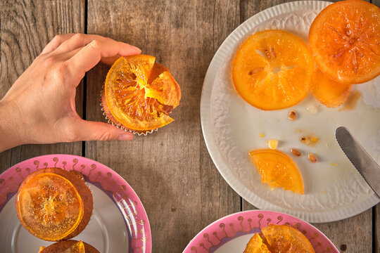 Woman's hand garnishing muffins with candied orange slices