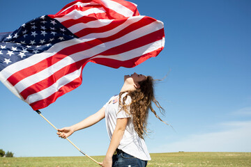 Happy girl holding American flag on field in remote landscape