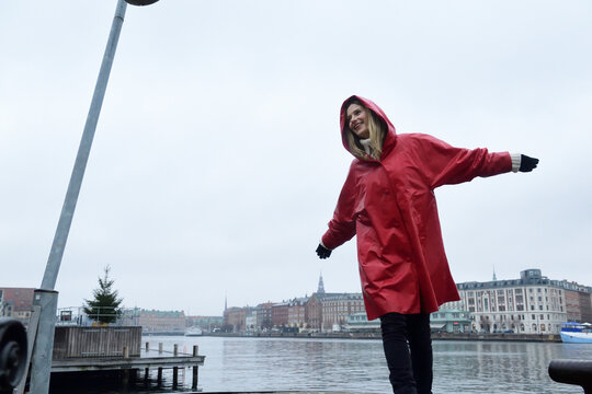 Denmark, Copenhagen, happy woman at the waterfront in rainy weather