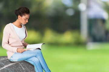 Woman holds book in her hands. Reading the book in a nature during beautiful sunset.