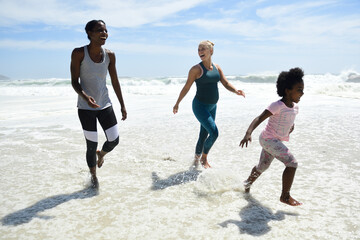 Mother with daughter and friend having fun in surf on the beach