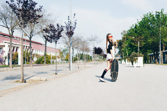 Spain, teenage girl with skateboard on a road