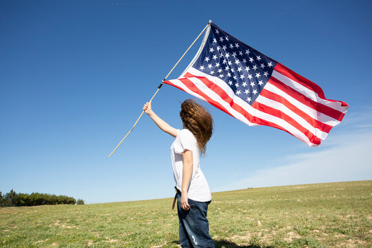 Girl holding American flag on field in remote landscape