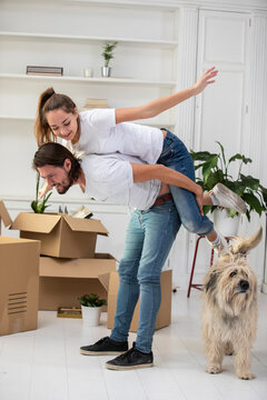 Happy couple with dog and cardboard boxes in new home