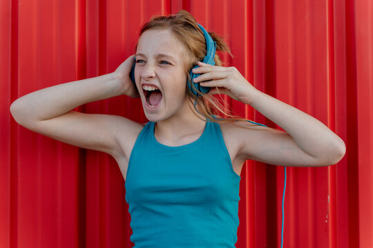 Girl with headphones in front of red wall