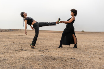 Young woman holding leg of other woman in bleak landscape