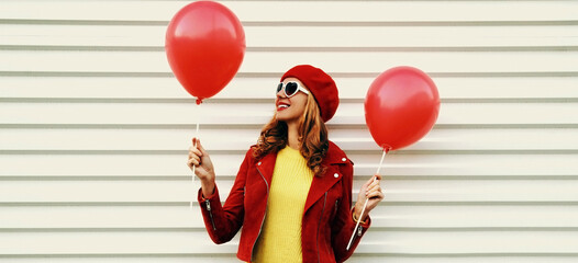 Portrait of happy smiling young woman with red balloons wearing a beret on white background