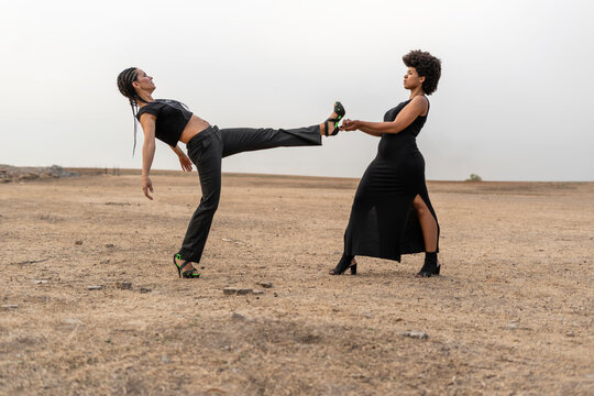 Young woman holding leg of other woman in bleak landscape