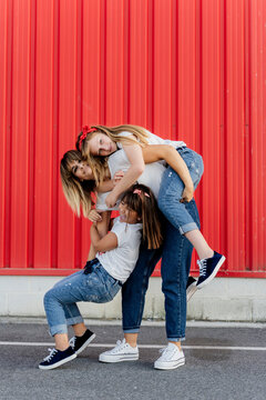 Mother playing with her daughters in front of red wall