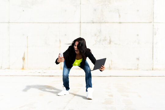 Woman holding smartphone and tablet, screaming and taking a selfie