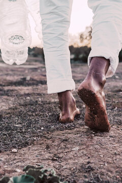 Close-up of man walking in barren land with empty plastic bottles