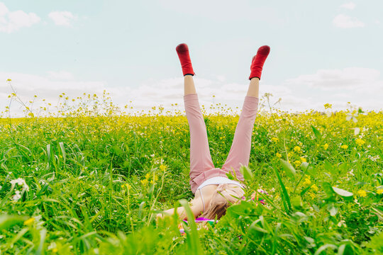 Naklejki Young woman wearing red ankle boots lying in a flower meadow in spring