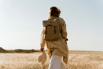 Rear view of female traveller with backpack on meadow