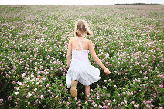 Rear view of a girl with braids running on clover field