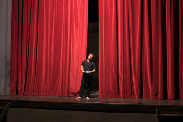 Barefoot actor with script standing on theatre stage