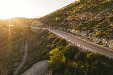 Italy, Elba Island, biker on coastal road against the sun, aerial view with drone