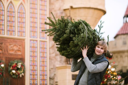 Smiling man with fir tree on his shoulder